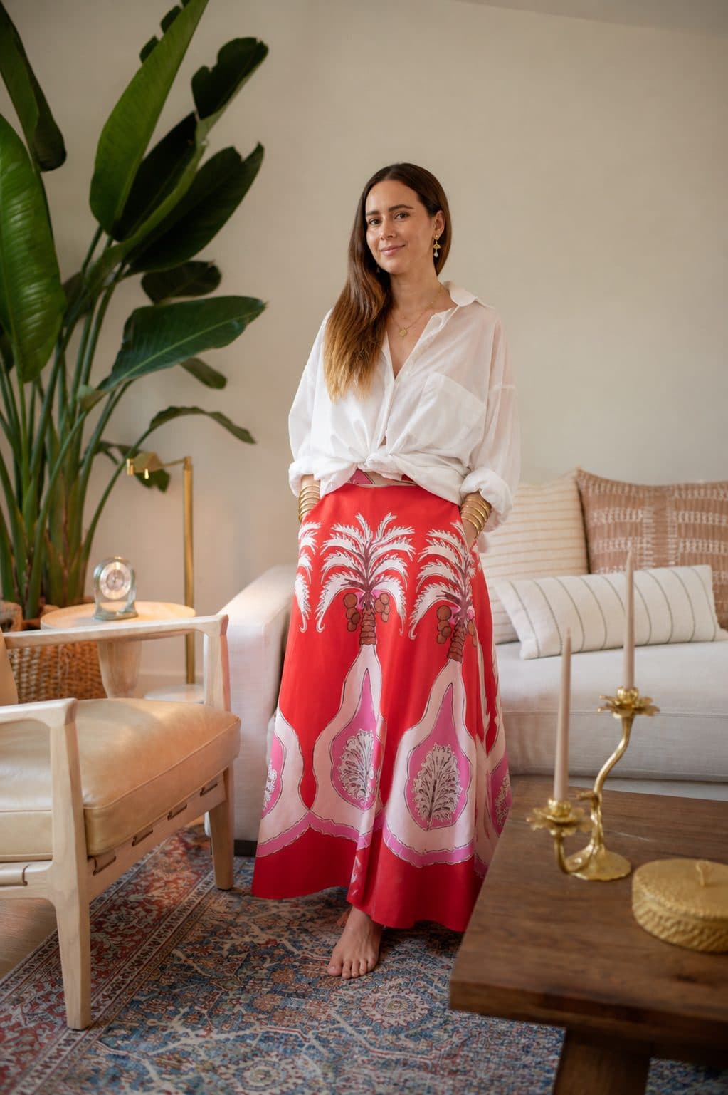Paula standing in a bright living room next to a large plant
