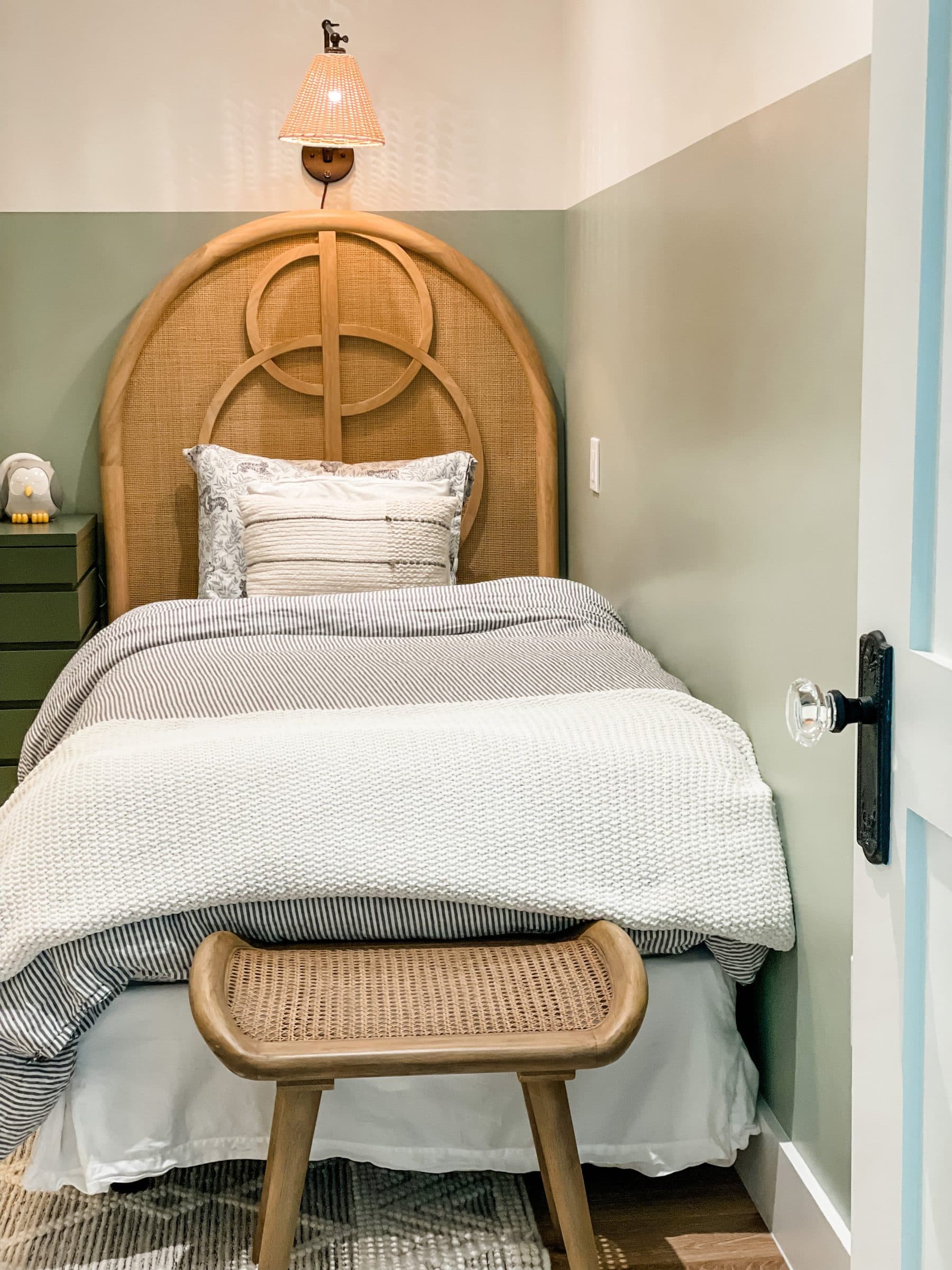 A calm bedroom with an arched rattan headboard and soft green walls