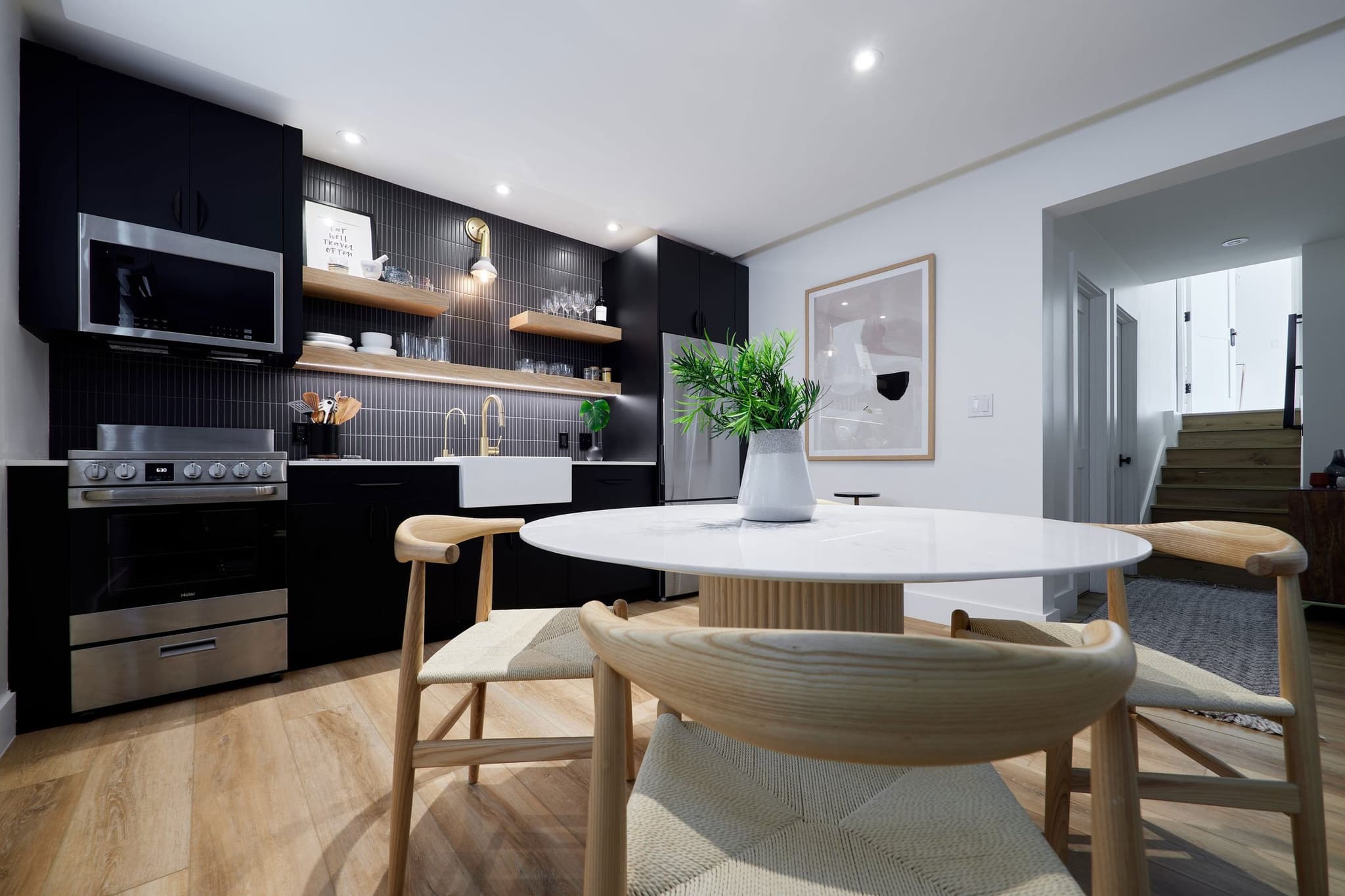 A kitchenette with dark cabinets, open shelves and a round table