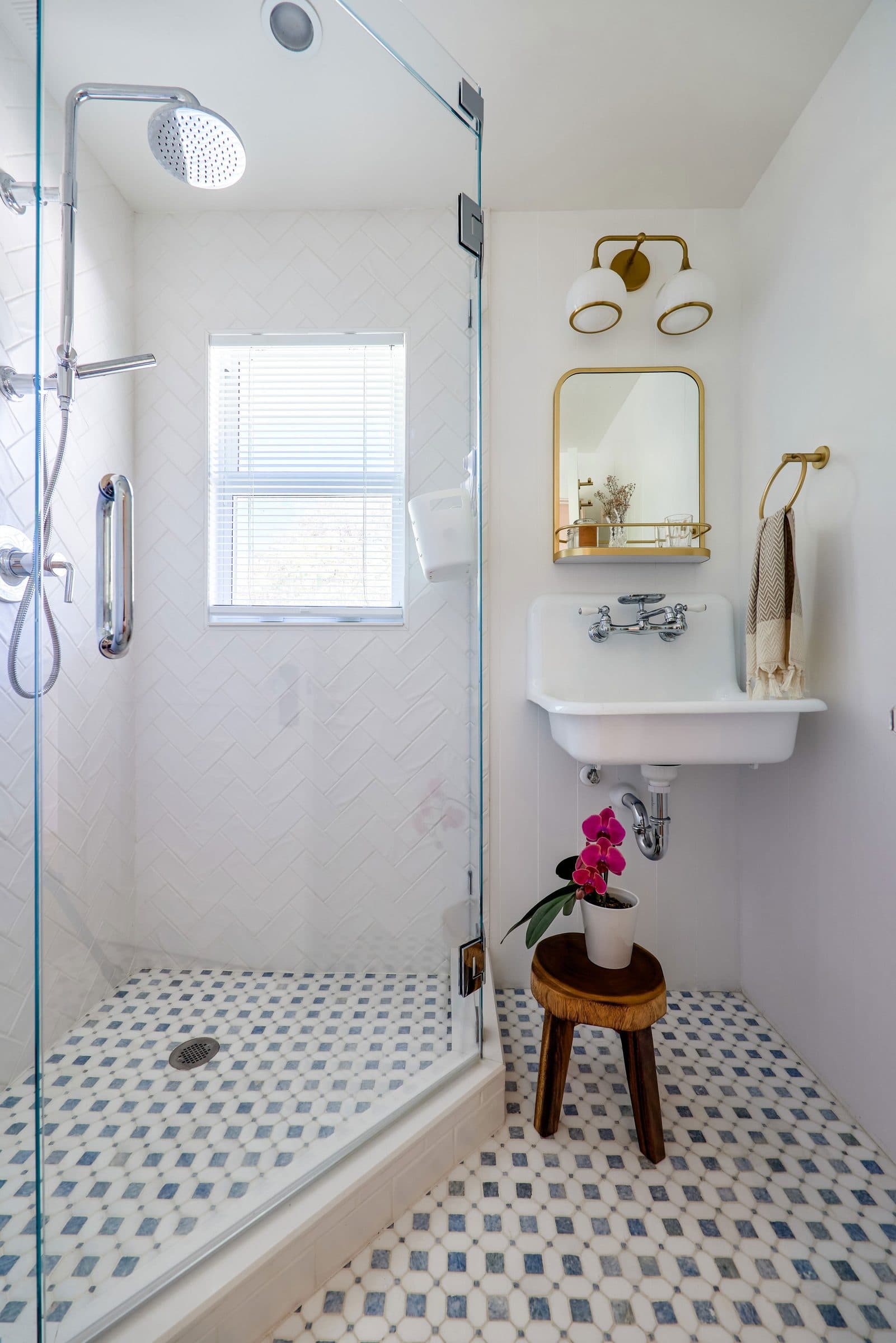 A bright bathroom with patterned floor tile and brass details