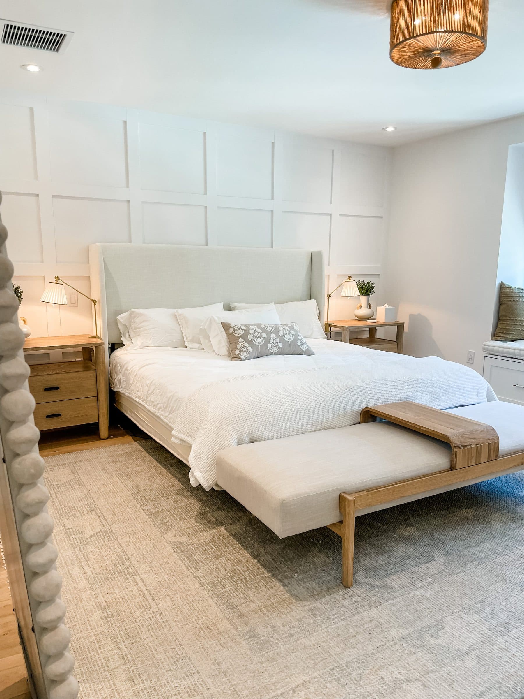 A calm bedroom with a paneled wall and a woven bench